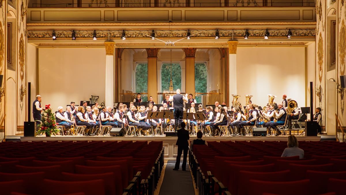 Photograph of an indoor concert hall with an orchestra performing under warm artificial lighting, illustrating white balance challenges in low light indoor photography.